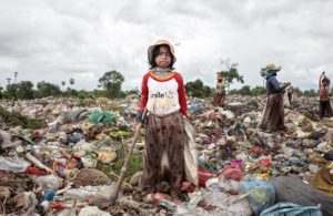 Seorang anak perempuan di Kamboja mengumpulkan sampah bekas. Foto via dailymail