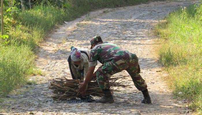 Salah satu anggota satgas TMMD di Desa Bodag, Kecamatan Kare, Kabupaten Madiun, Kapten Inf Agus Eko saat membantu seorang nenek mengangkat kayu bakar (29/7/2018)