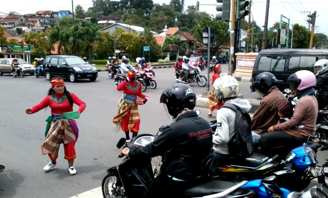 Para pegiat seni jathilan pamerken pertunjukkan di depan para pengendara motor di jalanan. Foto via Suaramerdeka