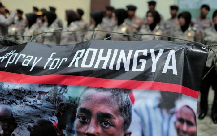 A banner is seen during a protest against what demonstrators say is the crackdown on ethnic Rohingya Muslims in Myanmar, as police stand guard in front of the Myanmar embassy in Jakarta, Indonesia November 25, 2016. REUTERS/Beawiharta