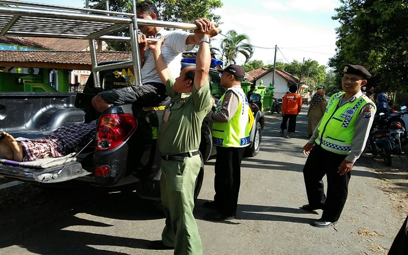 Aparat kepolisian dari Polres Ponorogo mengevakuasi seorang warga korban jatuh dari pohon Mahoni dan meninggal dunia. (Foto: Muh Nurcholis/NusantaraNews)