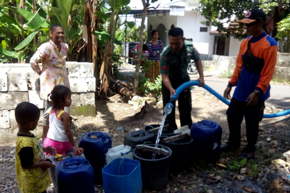 Danpos Koramil Grabagan Serma Asykur distribusikan air bersih kepada warga di Tuban. (Foto: Dok.Penrem)