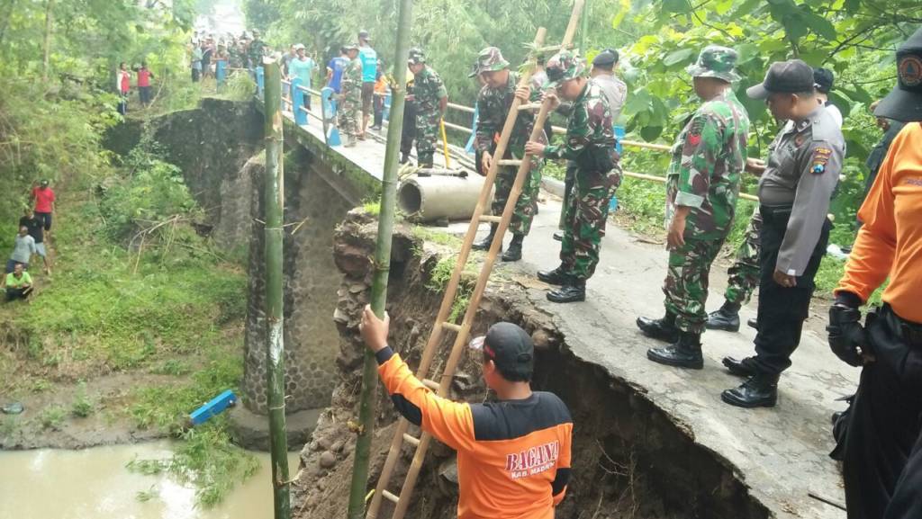 Anggota Kodim 0803 Madiun, Polres Madiun, BPBD (Badan Penanggulangan Bencana Daerah) dan Masyarakat Bersama sama kerja bhakti membuat tanggul sementara agar jalan bisa dilalui, Kamis (16/11). Foto: Arief Safuan/NusantaraNews