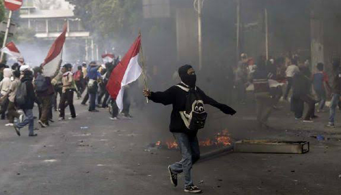 Seorang Pelajar STM Lari Membawa Bendera Merah Mutih Saat Ikut Demo Menolak Revisi UU KPK. (Foto Dok. CNN Indonesia)